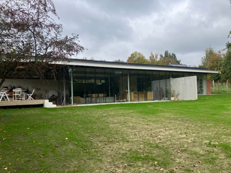 Nieuwbouwwoning in Deux-Acren met plat dak en glazen wanden aan de tuinkant, een project van Bouwwerken Goossens