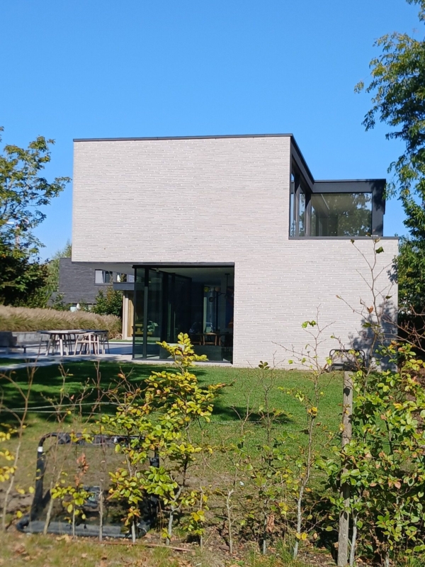 Tuinzijde van de nieuwbouwwoning in Lochristi met een terras voor de glazen wanden