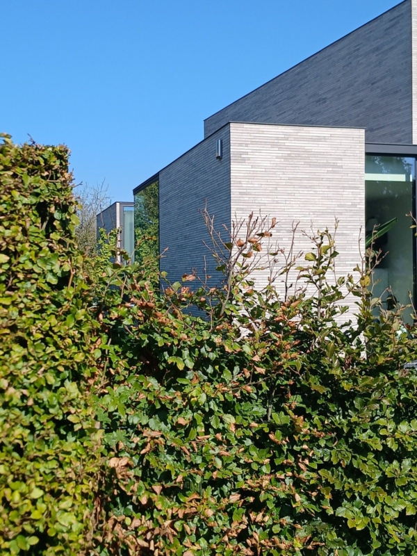 Rechthoekige blokken in lichtgrijze baksteen die naar voren en naar achteren springen, aan de nieuwbouwwoning in Lokeren