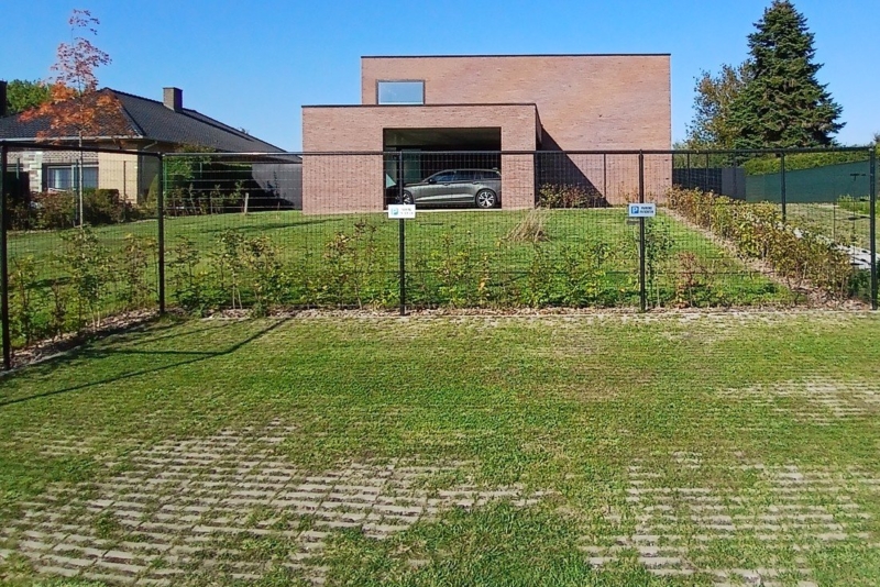 Vooraanzicht van de nieuwbouwwoning in Steenhuize met de brede opening van de overdekte autostaanplaats