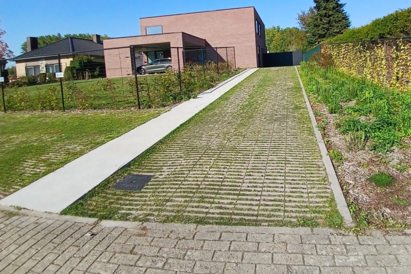 Oprit in grasdallen met betonnen pad naar de nieuwbouwwoning in Steenhuize