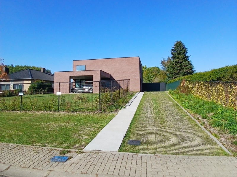 Nieuwbouwwoning in Steenhuize gezien vanaf de straat, met de oprit in grasdallen