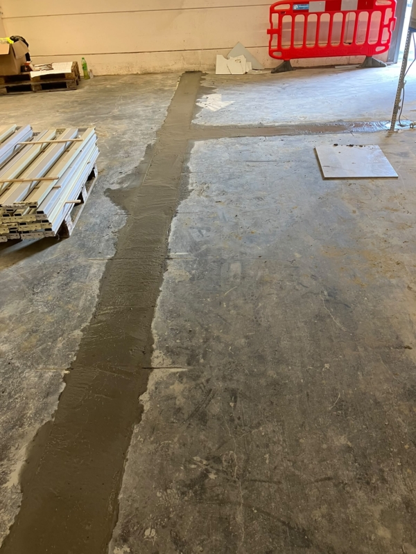 Gevulde sleuven in de betonvloer van een bedrijfsruimte, gelijk met de bestaande vloer, een project van Bouwwerken Goossens