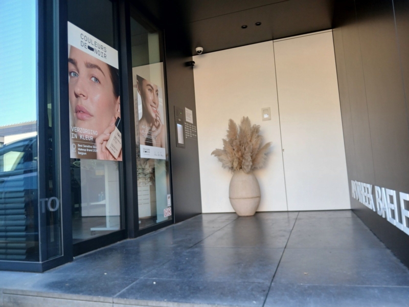 Inkom van de apotheek in Bavegem met een vloer in grote grijze tegels en lichte wanden