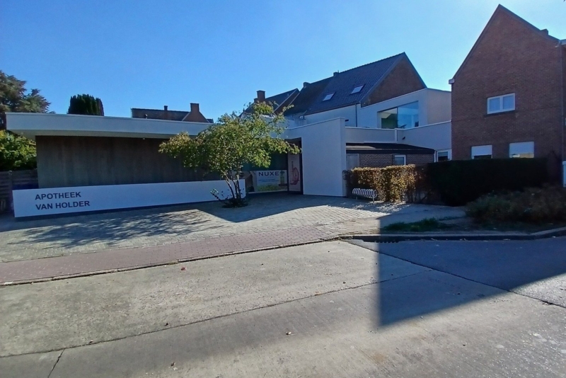 Achterzijde van de apotheek in Zottegem met een lage aanbouw met plat dak en een oprit in klinkers