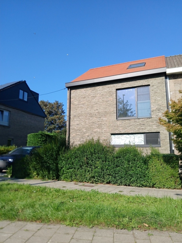 Halfopen woning in Gentbrugge met een oranje pannendak, een dakraam en een donkere dakrand