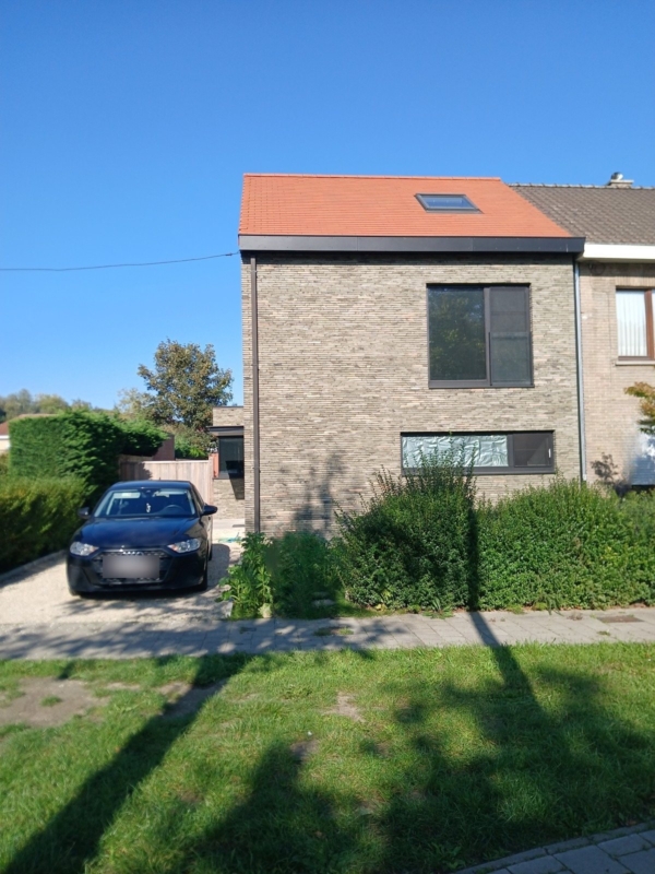 Voorgevel van de verbouwde woning in Gentbrugge met een groot raam op de verdieping en een breed, laag raam op het gelijkvloers