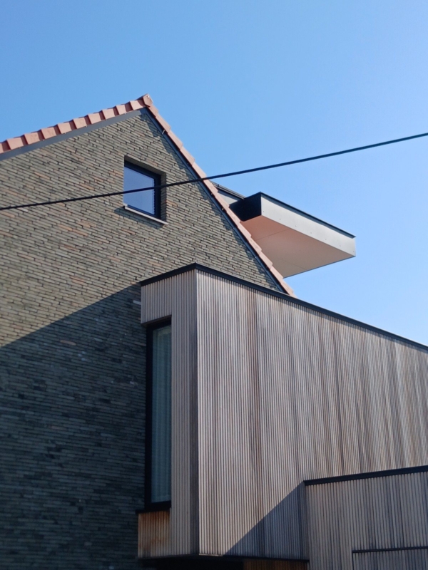 Detail van de verticale houten latten op de uitbouw en het uitstekende dakvolume, in Gentbrugge