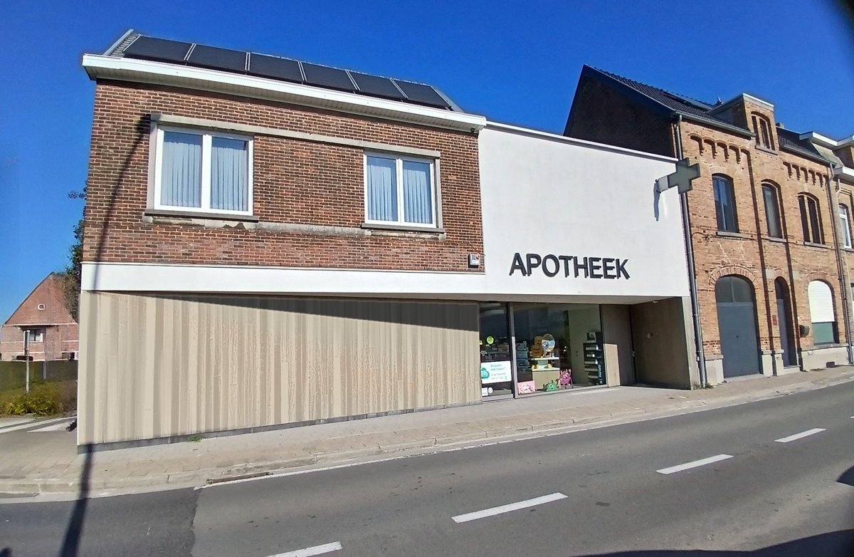 Verbouwde apotheek in een hoekpand in Zottegem met een grote witte gevel met de letters APOTHEEK en houten gevelbekleding op het gelijkvloers, een project van Bouwwerken Goossens