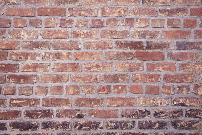 Oude bakstenen muur met verweerde voegen